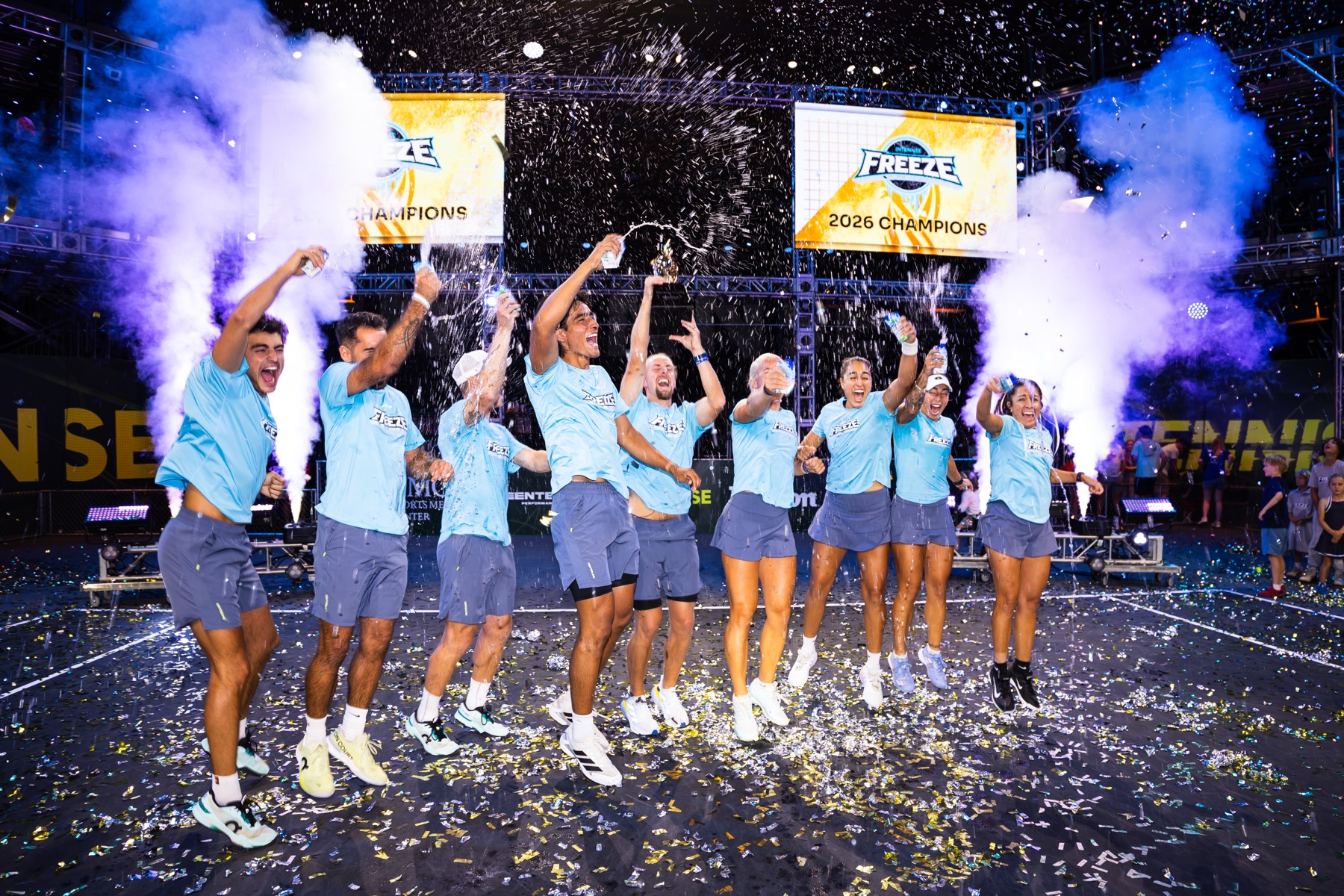 Players celebrating together on court under confetti and smoke at the close of Championship Weekend.